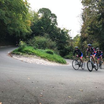 Three cyclists approaching hairpin on Box Hill, Surrey