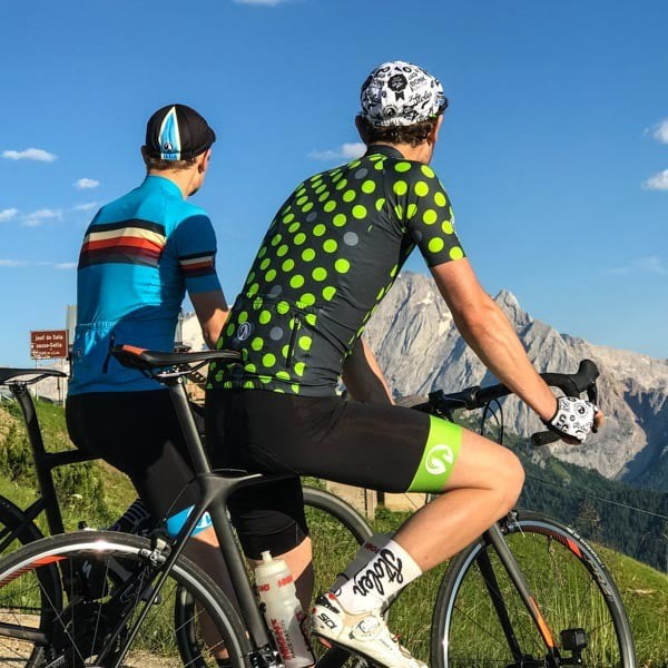 Two men wearing Stolen Goat caps and cycling clothing at sunset