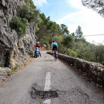 Narrow road from and to Port de Valldemossa Mallorca - cyclist and scooter slow to pass each other